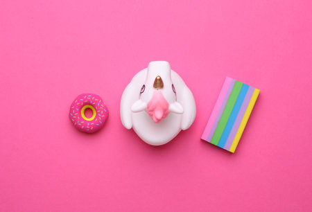 Rubber bath unicorn with donut and rainbow on pink background. Top view.の写真素材