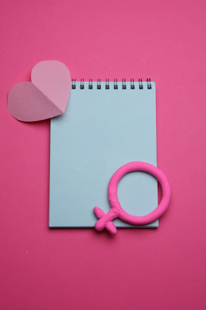 Female gender symbol with notebook and heart on pink background. Love conceptの写真素材