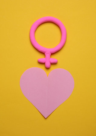 Female gender symbols made of plasticine with heart on yellow background. Love conceptの写真素材