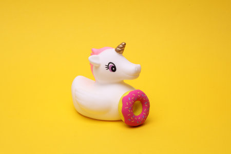 Rubber bath unicorn with donut on a yellow background.の写真素材
