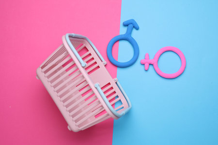 Supermarket basket with female and male gender symbols on blue pink backgroundの写真素材
