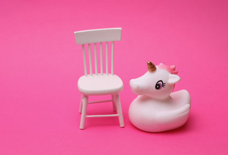 Rubber unicorn with chair on pink backgroundの写真素材
