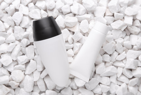 White antiperspirant stick and cream tube on pebblesの写真素材