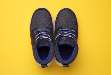 Children's warm sneakers half-boots on a yellow backgroundの写真素材