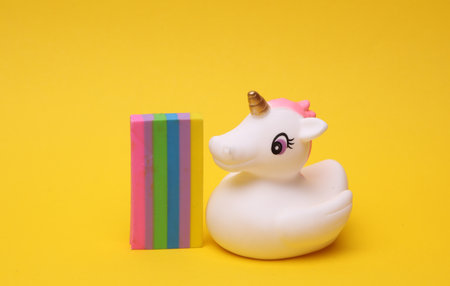 Rubber unicorn with rainbow on yellow background. Creative ideaの写真素材