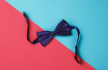 Bow tie on colored paper background. Top view.