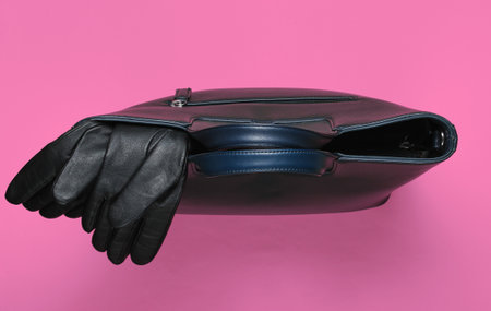 Leather bag and gloves on pink paper background. Minimalistic fashion still life. Flat lay. Top view