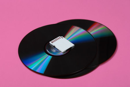SD memory card, cd drives on pink paper background. Modern and obsolete storage. Top view