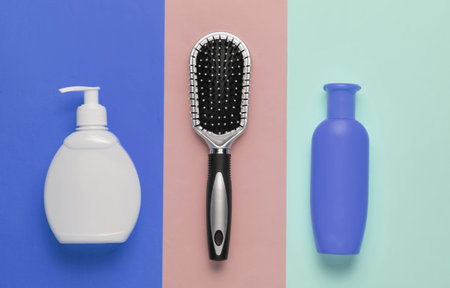 Minimalistic beauty concept. Hair care. Comb and bottles of shampoo on colored pastel background. Top viewの写真素材
