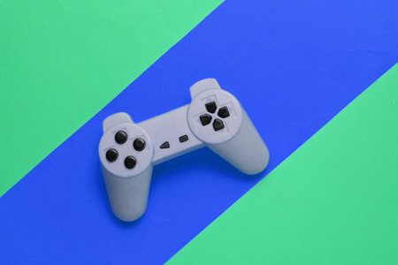 Retro gamepad on a colored paper background. Entertainment 90s. Top view.