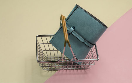 Minimalistic shopping concept. Mini shopping basket and leather wallet on colored background.
