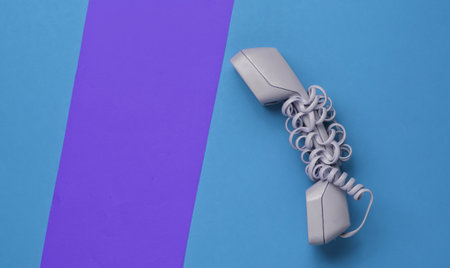 Handset wrapped cable on colored paper background. Minimalistic office concept. Top view