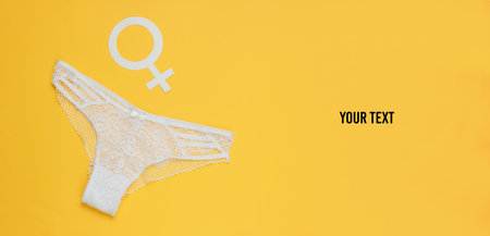 Women's sexy lace panties and gender Femen symbol on yellow background with space for your text. The concept of feminism. Top viewの写真素材