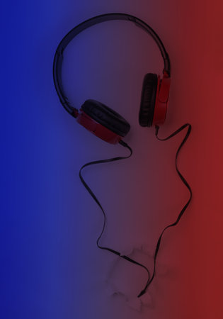 Stylish wired headphones in blue red gradient background with torn hole. Top view. Music lover...