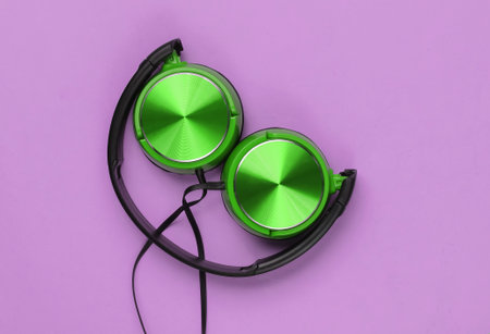Stylish wired green headphones on pink background. Top view