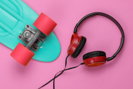 Cruiser board, headphones on pink background. Summer fun. Retro style. 80s. Top view