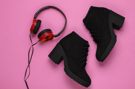 Women's winter boots with headphones on pink background. Top view