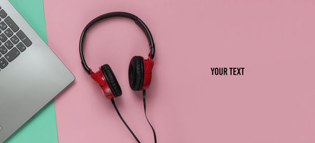 Laptop and dj headphones on blue pink pastel. Copy space. Top view
