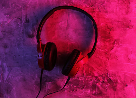 Wired headphones on concrete background. Neon blue-red gradient light. Retro wave, 80s pop culture....