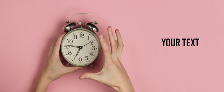 Creative flat lay morning time emotions concept. Copy space. Angry female hand holds retro alarm...