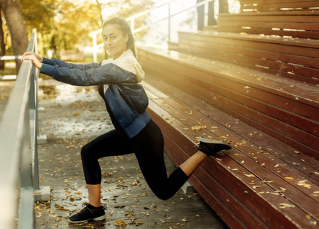 Fit slim woman is practicing leg stretching. Outdoor training. Healthy lifestyle concept