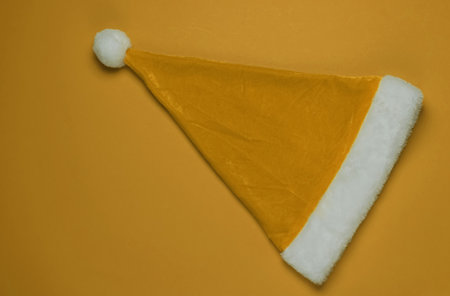 Santa hat on yellow background. New Year, Christmas minimalistic concept. Top view, studio shot.