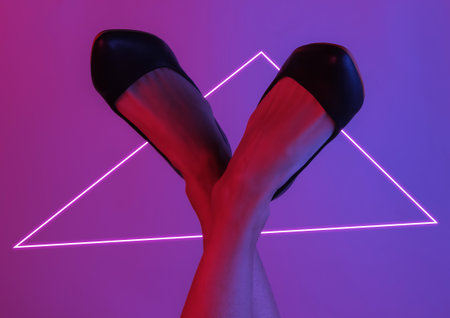 Women's legs with classic high heel shoes. Creative pop art pink blue neon color. Trendy gradient illumination. Night lightの写真素材