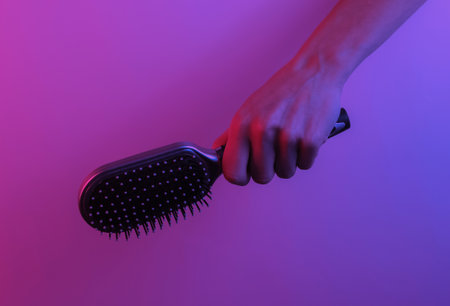 Hand holds hair comb. Creative pop art pink blue neon color. Trendy gradient illumination. Night...