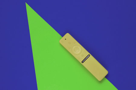 Modern tv remote in a case on colored paper background with geometric shapes. Top view. Fashion conceptの写真素材