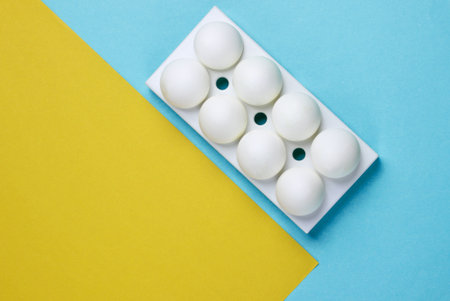Tray with white chicken eggs on colored background. Minimalistic food concept. Top viewの写真素材