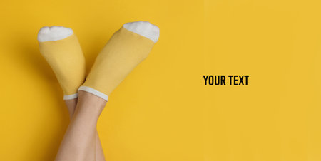 Female legs with yellow socks on yellow studio background. Minimalistic fashion concept. Top view. Copy spaceの写真素材