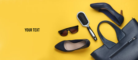 Flat lay style women's accessories on yellow background. Bag, leather high heel shoes, sunglasses,...