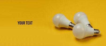 Three LED light bulbs on yellow background with space for your text