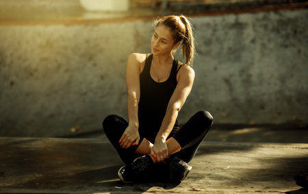 Attractive fit woman in sportswear resting while sitting in sports parkの写真素材