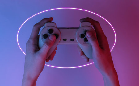 Gamer concept. Hand holds gamepad. Creative pop art pink blue neon color. Trendy gradient...