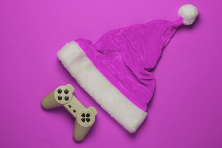 Santa hat and gamepad on pink background. Gamer concept. Christmas holidays