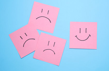 Unhappy and happy faces on square memo papers, blue background. Business concept