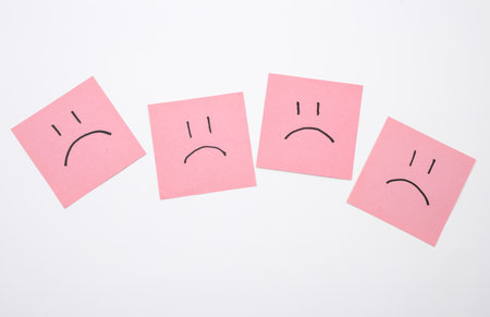 Happy and unhappy faces on square memo papers, white background. Business conceptの写真素材