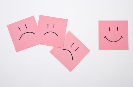 Happy and unhappy faces on square memo papers, white background. Business concept