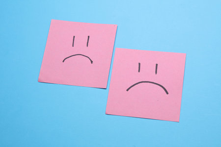 Unhappy faces on square memo papers, blue background. Business concept