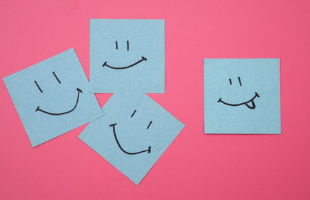 Happy faces on square memo papers, pink background. Business concept