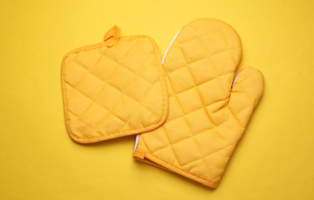 Yellow oven mitts on yellow background. Top view, flat layの写真素材