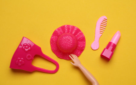 Doll accessories on yellow background. Beauty and fashion, travel concept. Flat lay