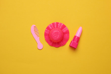 Doll accessories on yellow background. Beauty and fashion, travel concept. Flat lay