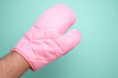 Hand in pink glove on a turquoise background, close-upの写真素材