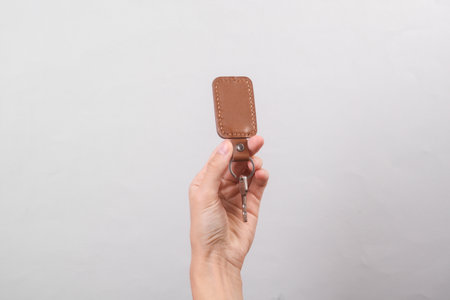 Leather keychain with key in female hand on gray backgroundの写真素材