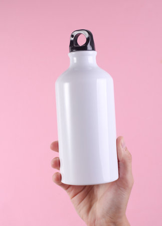 White metal water flask, thermos bottle in hand on pink background. Mockup for design