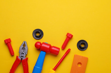 Set of children's toy tools on a yellow background. Flat lay