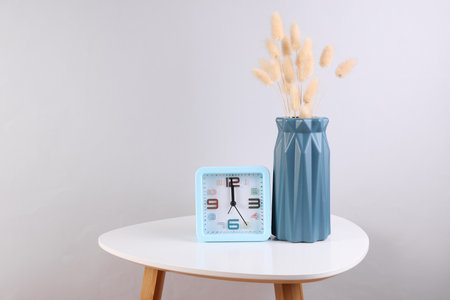 Vase with dried flowers and alarm clock on a coffee tableの写真素材