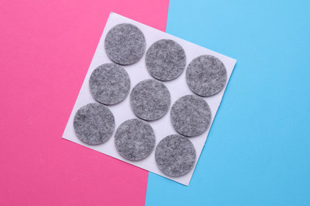 Felt protective circle pads for furniture on pink blue background